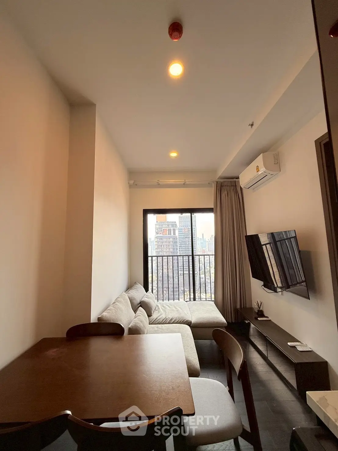 Modern living room with city view, cozy sofa, and wall-mounted TV in a stylish apartment.