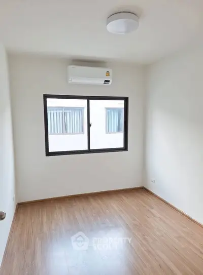 Minimalist empty room with wooden floor and air conditioning, perfect for customization.