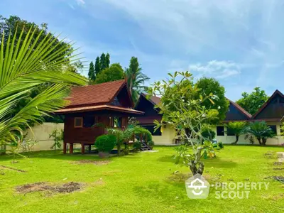 Charming tropical garden with traditional wooden houses under a clear blue sky.