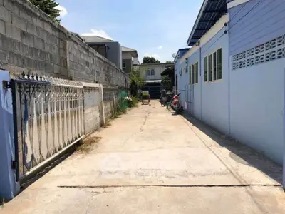Spacious driveway leading to a residential property with blue exterior walls and secure gate.