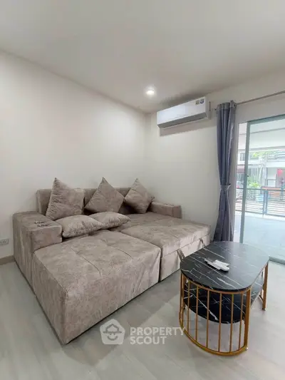 Modern living room with stylish sofa and coffee table, featuring a sleek air conditioning unit and large window.