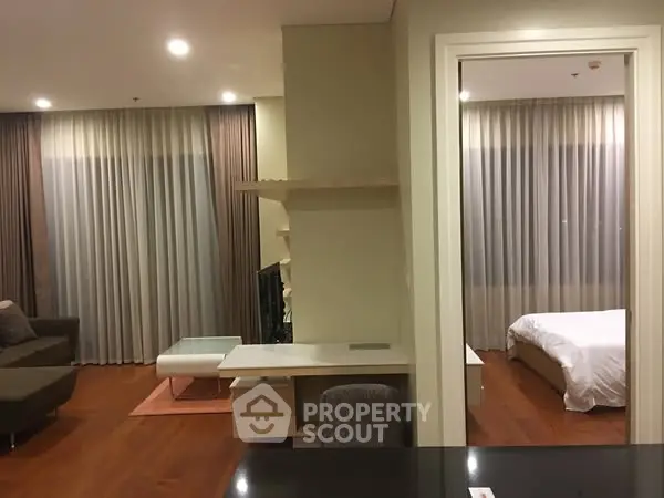 Modern apartment interior with cozy living room and bedroom, featuring elegant curtains and wooden flooring.