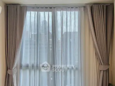 Elegant window with sheer curtains offering a cityscape view, perfect for modern living spaces.