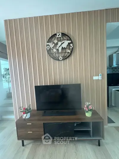 Modern living room with stylish TV stand and wall clock, featuring elegant decor and wooden paneling.