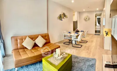 Modern living room with stylish decor and open dining area, featuring cozy seating and elegant lighting.