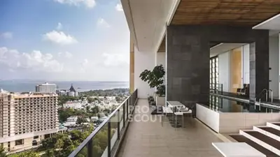 Luxurious balcony with stunning city and ocean view, featuring modern seating and pool area.