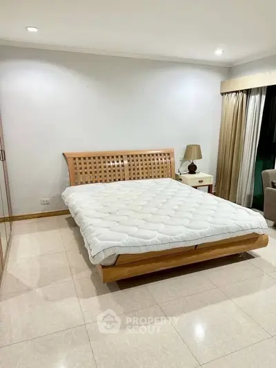 Spacious bedroom with elegant wooden bed and cozy lighting, perfect for relaxation.
