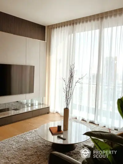 Elegant living room with floor-to-ceiling windows draped in sheer curtains, modern furnishings, and a serene ambiance.