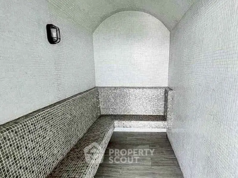 Luxurious steam room with elegant mosaic tiles and cozy seating area.