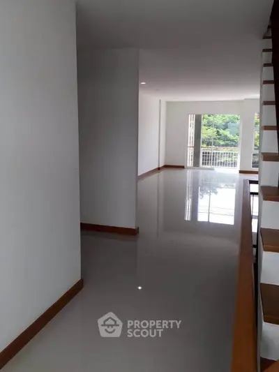 Spacious modern interior with glossy floors and large windows offering natural light and greenery views.
