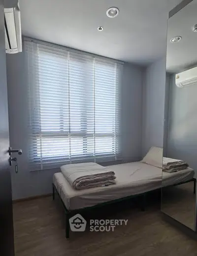 Cozy minimalist bedroom with natural light and modern air conditioning.