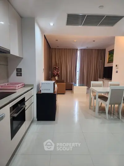 Modern open-layout kitchen and living room with sleek furniture and elegant decor.