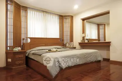 Elegant bedroom with wooden accents and large mirror, perfect for a cozy retreat.