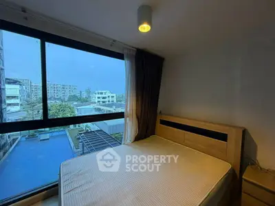 Modern bedroom with large window offering pool view in urban apartment