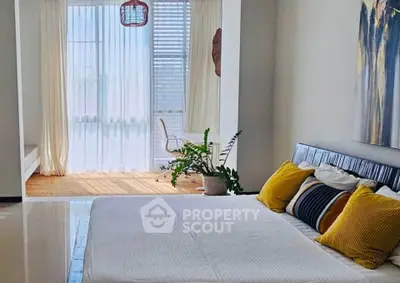 Spacious bedroom with modern decor and large windows offering natural light.