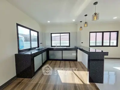 Modern kitchen with sleek black countertops and stylish pendant lighting in a spacious open layout.