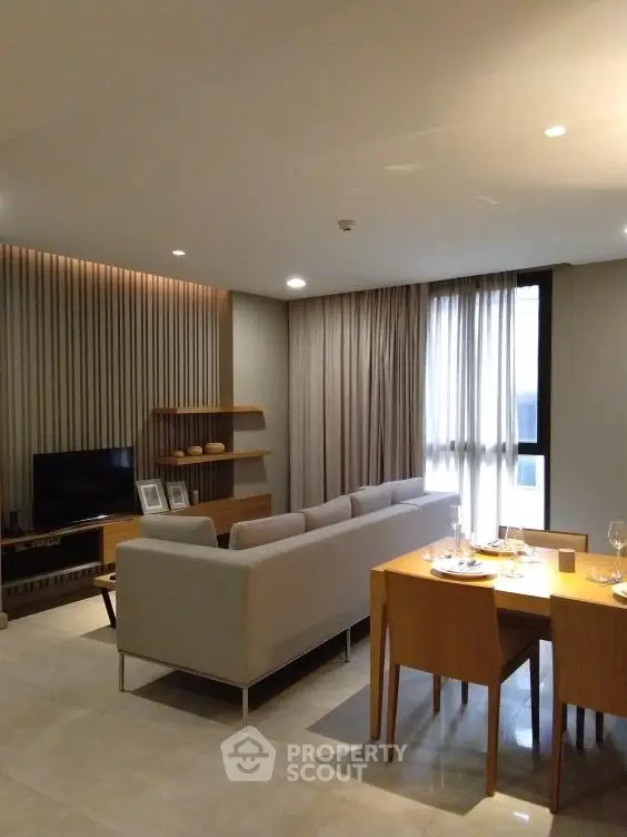 Modern living room with elegant decor and dining area, featuring a cozy sofa and stylish wooden furniture.