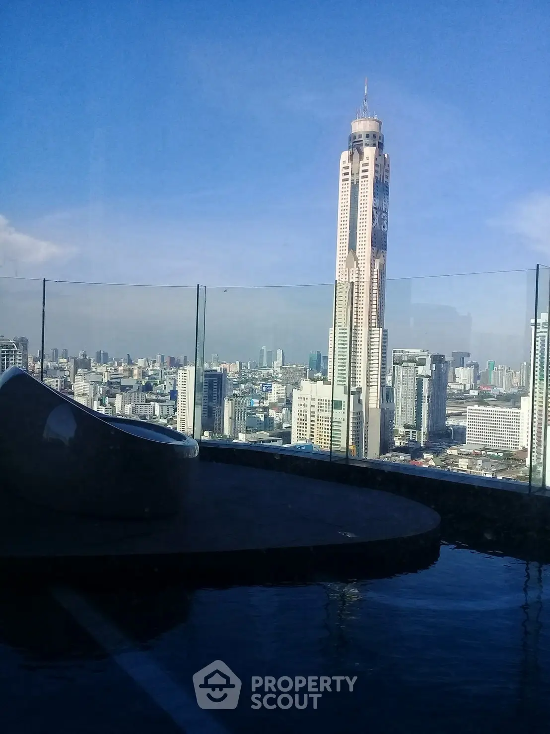 Stunning cityscape view from a rooftop pool with glass railing.