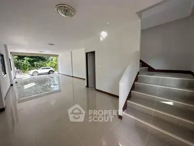 Spacious open-plan living area with modern staircase and large windows.