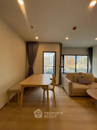 Modern living room with city view, wooden flooring, and stylish furniture