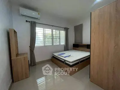 Spacious bedroom with modern furnishings and natural light, featuring a sleek air conditioning unit.