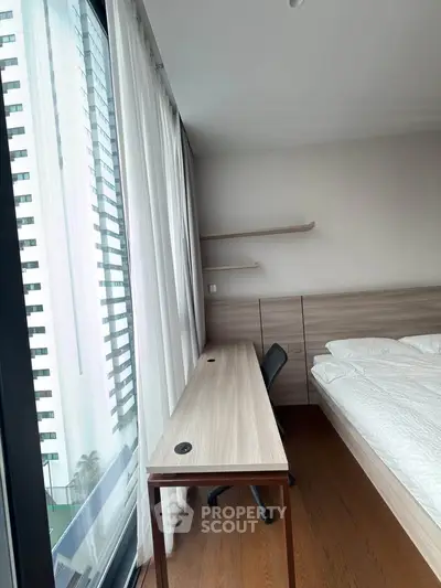 Modern bedroom with large window and study desk in high-rise apartment