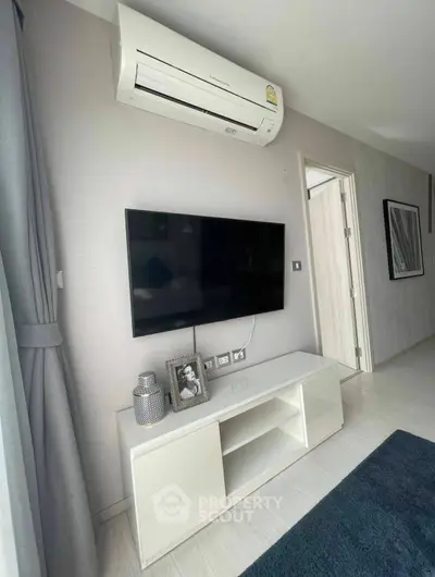 Modern living room with wall-mounted TV and air conditioning unit, featuring sleek furniture and stylish decor.