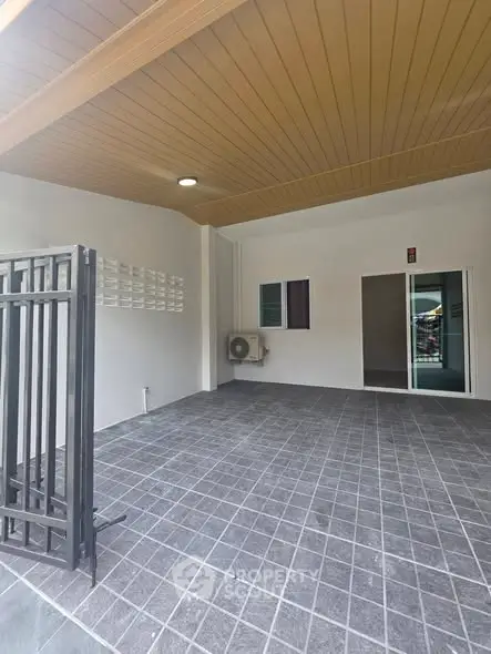 Spacious covered parking area with modern design and tiled flooring in a residential property.
