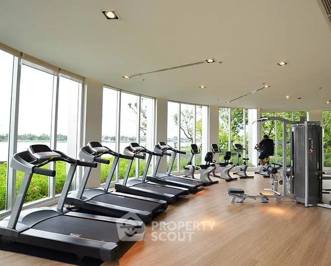 Modern gym with large windows and state-of-the-art equipment overlooking greenery.