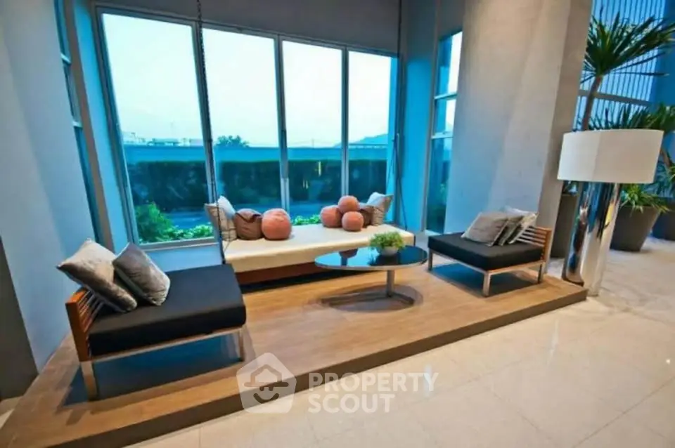 Modern living room with large windows and stylish furniture, offering a serene view and elegant decor.