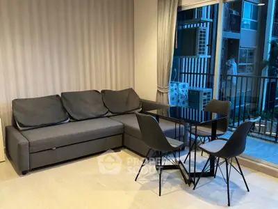 Modern living room with sleek gray sofa and dining set near balcony view.