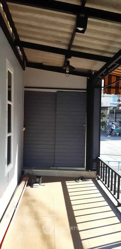 Charming covered balcony with urban street view, perfect for relaxation and outdoor enjoyment.