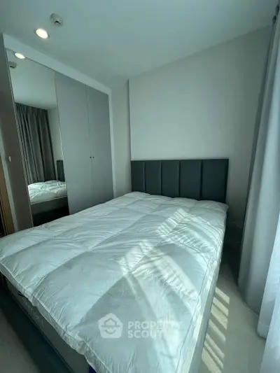 Cozy bedroom with modern design and ample natural light, featuring a comfortable bed and sleek wardrobe.