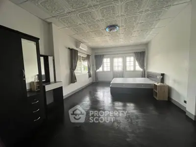 Spacious bedroom with elegant ceiling design and large windows for natural light.