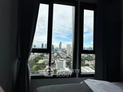 Stunning cityscape view from a high-rise bedroom window, showcasing urban skyline and lush greenery.