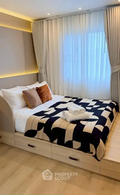 Modern bedroom with stylish decor and natural light, featuring a cozy bed and elegant curtains.