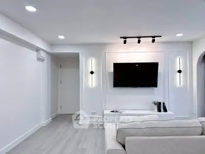 Modern living room with sleek design, wall-mounted TV, and elegant lighting fixtures.