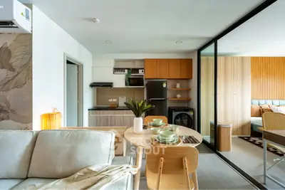 Modern open-plan living room with kitchen and dining area, featuring stylish decor and natural light.