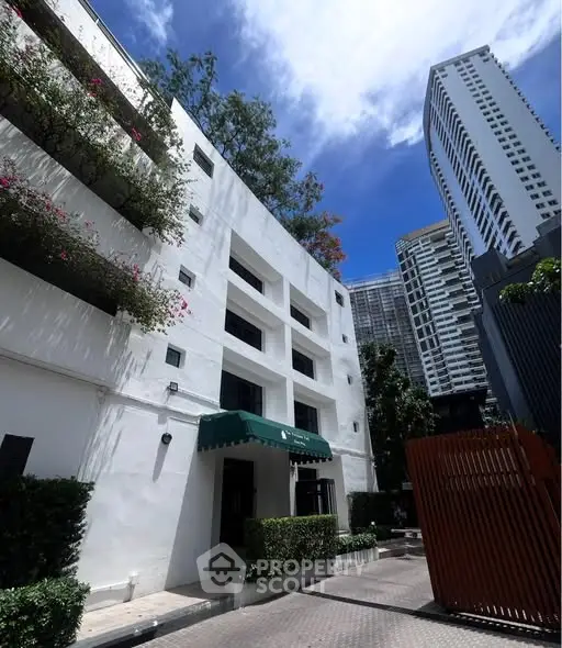 Modern urban building exterior with lush greenery and blue sky backdrop