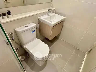 Modern bathroom with sleek fixtures and minimalist design, featuring a compact sink and toilet.