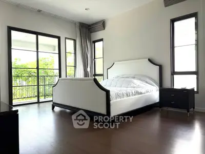 Spacious bedroom with elegant bed and large windows overlooking greenery.