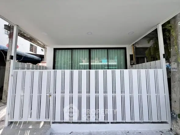 Modern exterior with sleek white fence and large window for stylish urban living.
