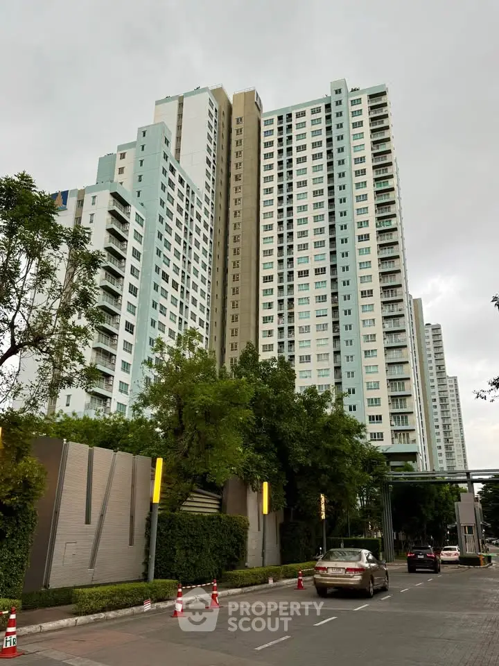 Modern high-rise residential building with lush greenery and street view.