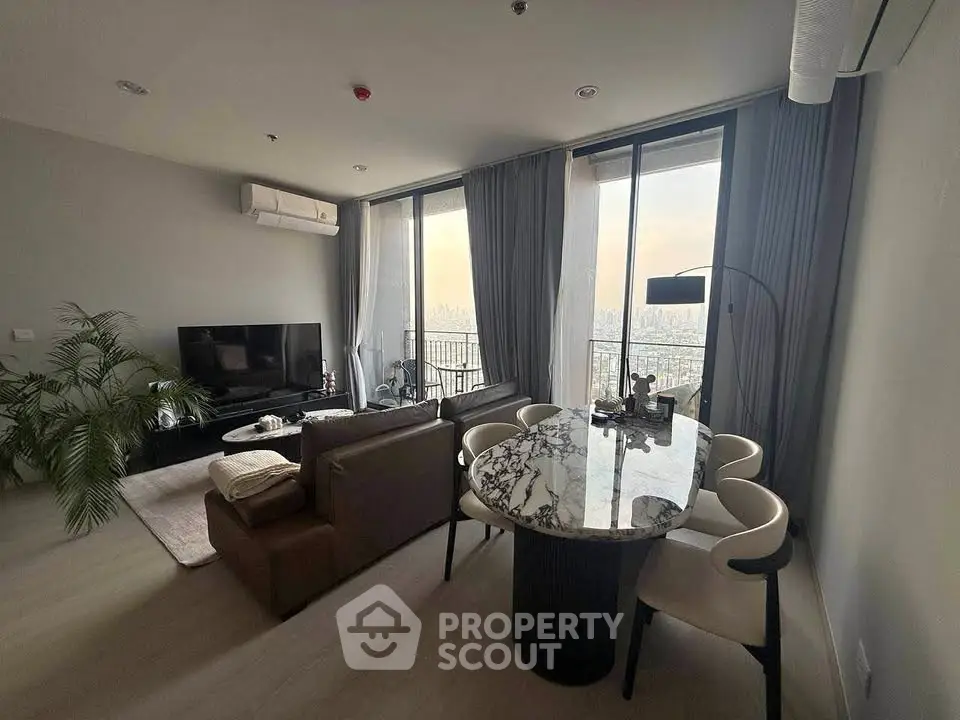 Modern living room with city view, featuring elegant furniture and large windows.