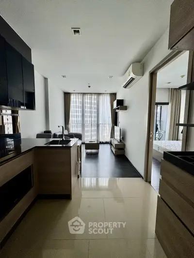Modern apartment interior with open kitchen and living area, featuring sleek design and large windows.