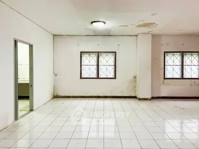 Spacious empty room with tiled floor and two windows, ideal for renovation.