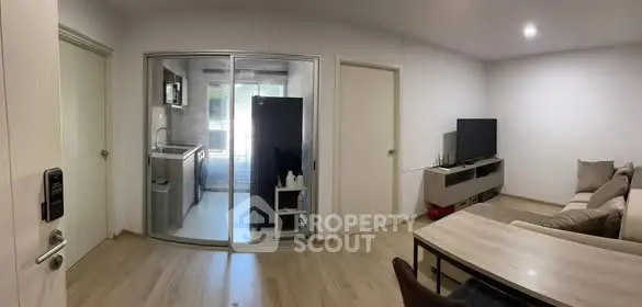 Modern living room with glass-enclosed kitchen, sleek furniture, and cozy ambiance.