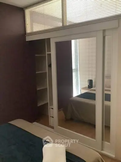 Cozy bedroom with mirrored closet doors and built-in shelving, perfect for modern living.