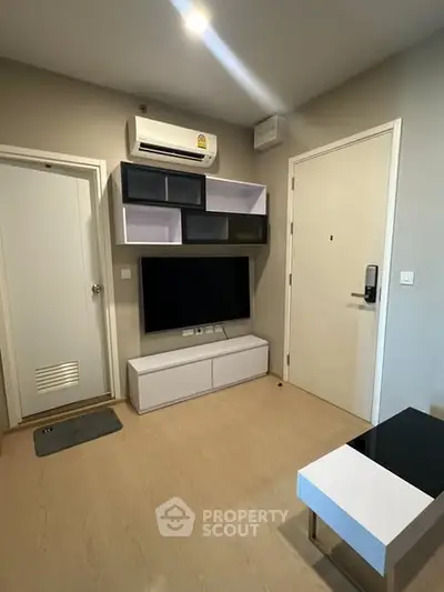 Modern living room with sleek furniture and wall-mounted TV in a cozy apartment.