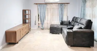 Spacious living room with modern gray sofa and elegant wooden furniture, perfect for relaxation.
